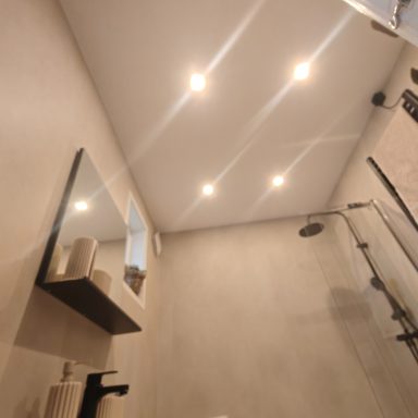Moderne badkamer met inbouwverlichting, spiegel en douche.