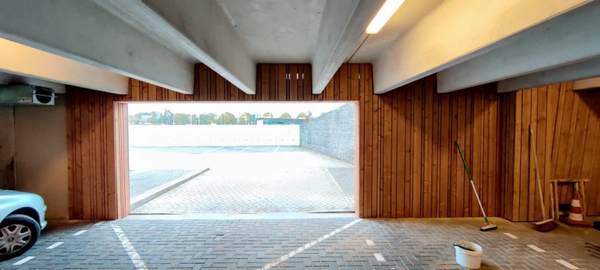 Gevelbekleding utrecht Een modern, ruim parkeerterrein met houten wanden en een grote opening naar buiten.