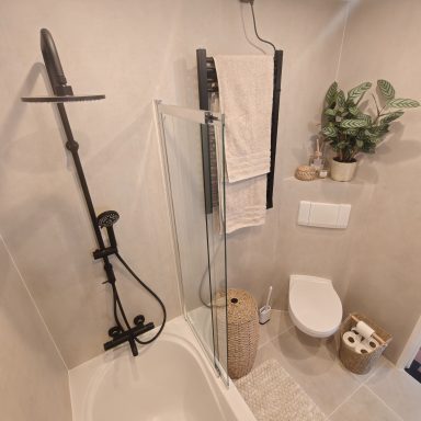 Moderne badkamer met doucheruimte, toilet, handdoeken en planten.