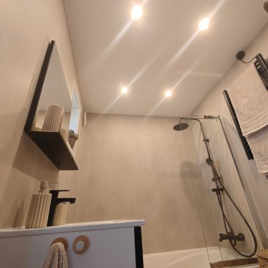 Moderne badkamer met douche, spiegels en inbouwverlichting op de muur.